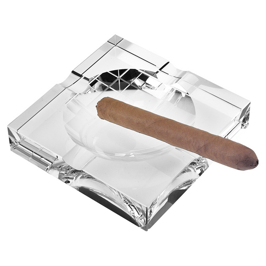 Clear crystal square tabletop cigar ashtray with an elegant clear design and a cigar resting on it.