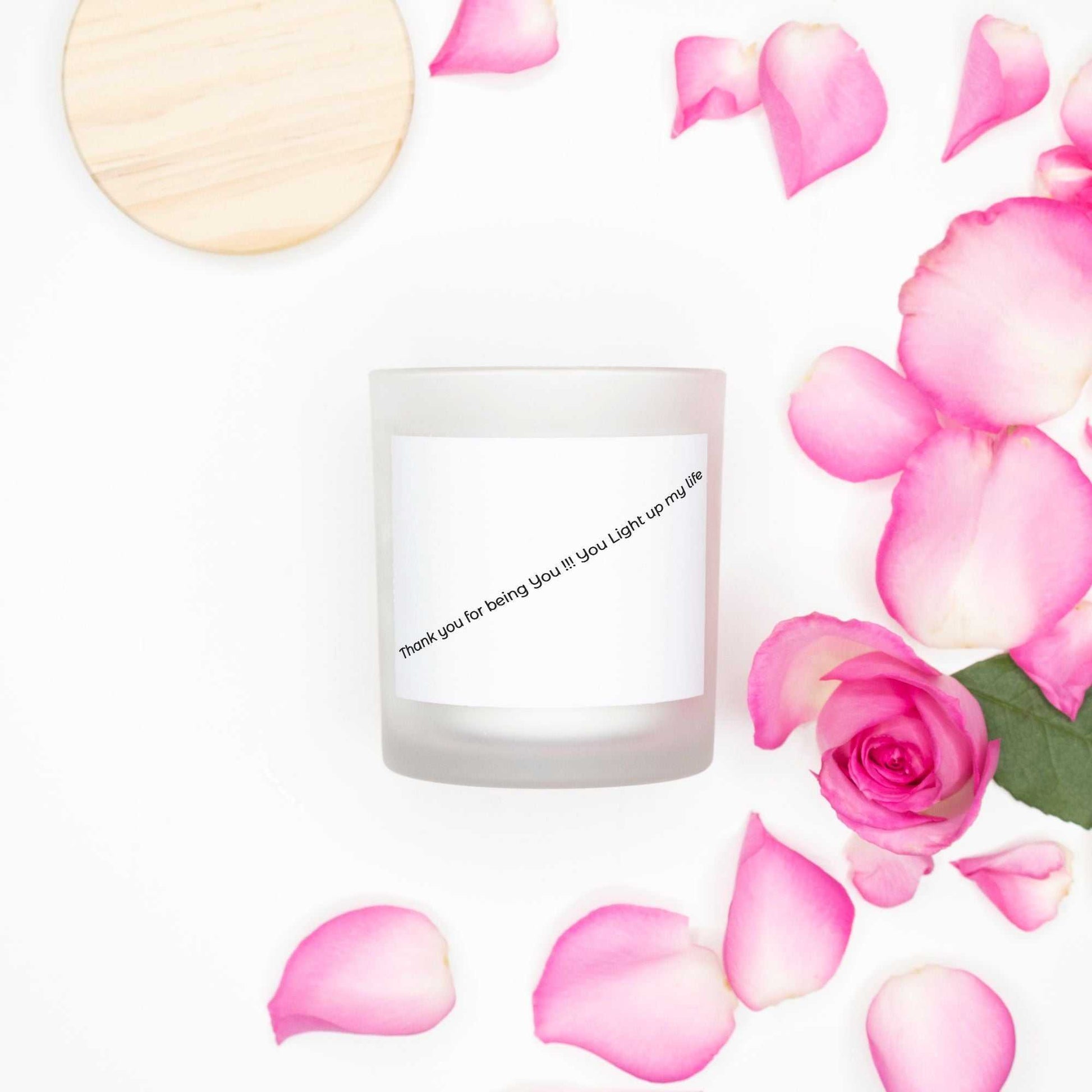Pink Wick Frosted Candle with wooden lid surrounded by pink rose petals and petals scattered on white background