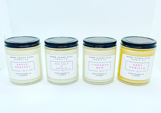 Set of four Home Scape Candles in clear jars with black lids, featuring scents Apple Harvest, Sea Salt & Orchid, Cinnamon Bun, and Very Vanilla, hand-poured in Illinois.